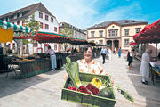Eine Marktfrau zeigt eine Kiste mit Produkten (Foto: Rothe)