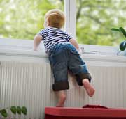 Ein Kind schaut vom beheizten Zimmer durch ein Fenster ins Freie. 