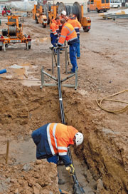 Arbeiter in der Baugrube verbinden Kabel aus dem Holz-Heizkraftwerk mit dem Stromnetz