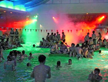 Jugendliche im von farbigen Scheinwerfen beleuchteten Schwimmbad 