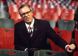 Georg Schramm sitzt im Zuschauerraum zwischen roten und schwarzen Stühlen.