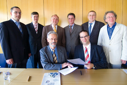 Acht Männer, Zwei Parteien, ein Vertrag - nach der Unterzeichnung der Grundsatzerklärung lächeln die Unterzeichner zufrieden in die Kamera.