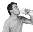 Junger Mann trinkt Wasser aus einer Flasche