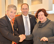 Sven Becker, Michael Teigeler, und Dr. Birgit Mack besiegeln den Kooperationsvertrag in der Messehalle mit einem Handschlag.