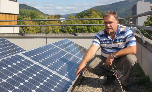 Lehrer Martin Hammerich auf dem Schuldach negen einem Solarpanel