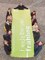 Das Festival-Team des Heidelberger Frühlings hält eine Fahne in den Händen.