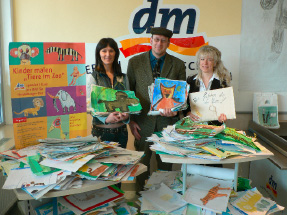 Zoodirektor Dr. Klaus Wünnemann mit Drogerie-Mitarbeiterinnen und Gemälden der Kinder 