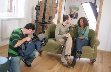 Eine junge Schauspielerin wird auf dem Sofa sitzend gefilmt.